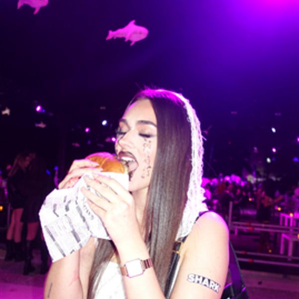 Clienta mordiendo una hamburguesa de Q Street Food en una fiesta
