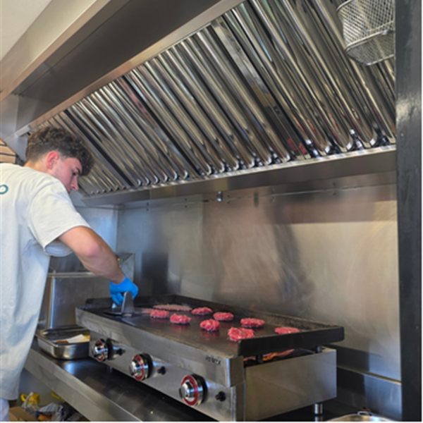 Cocinero de Q Street Food preparando hamburguesas en la plancha del truck